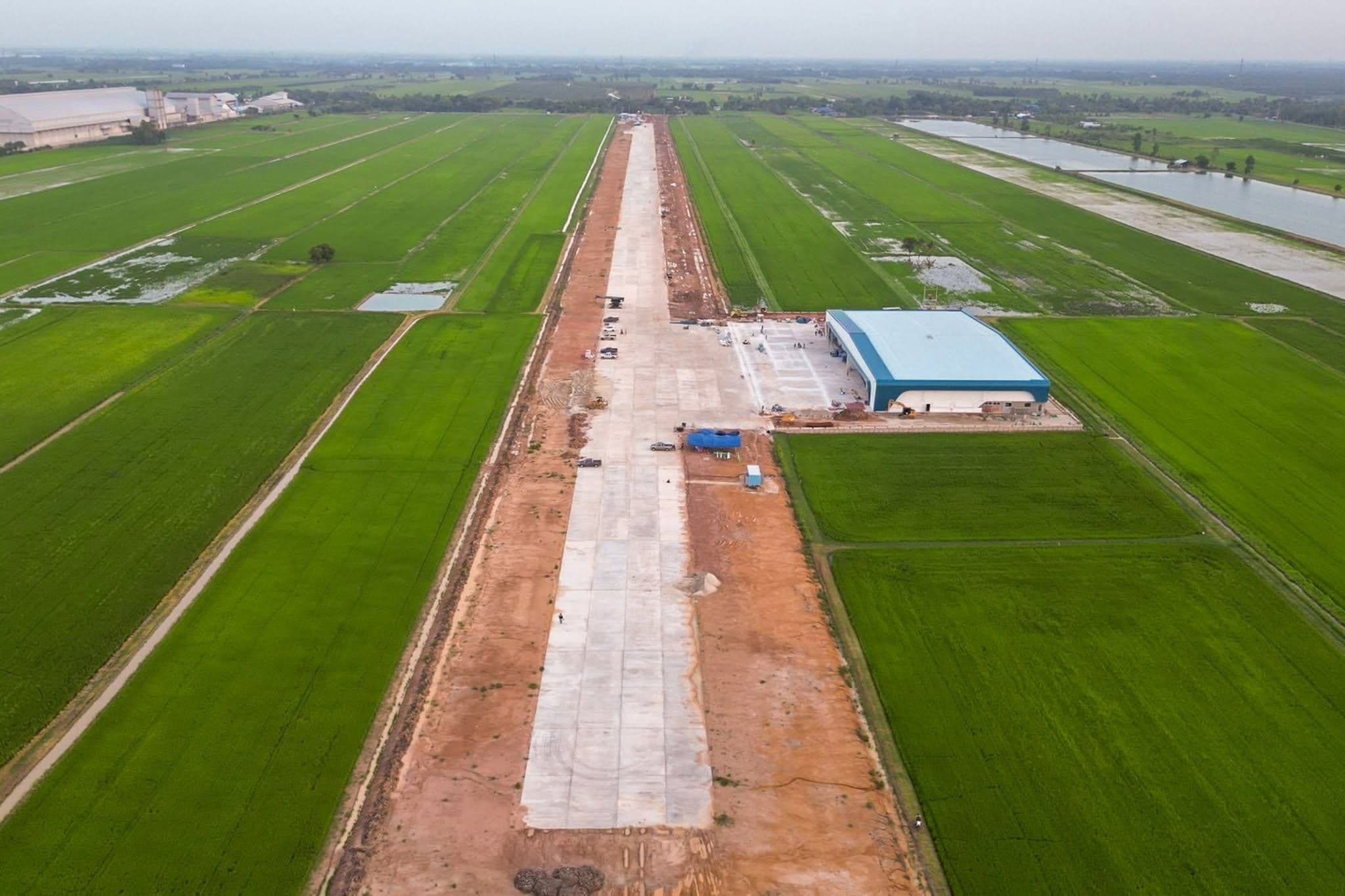 Guardian Blue Airport from the air: the runway running through open rice fields, with the blue-roofed hangar and apron alongside it.